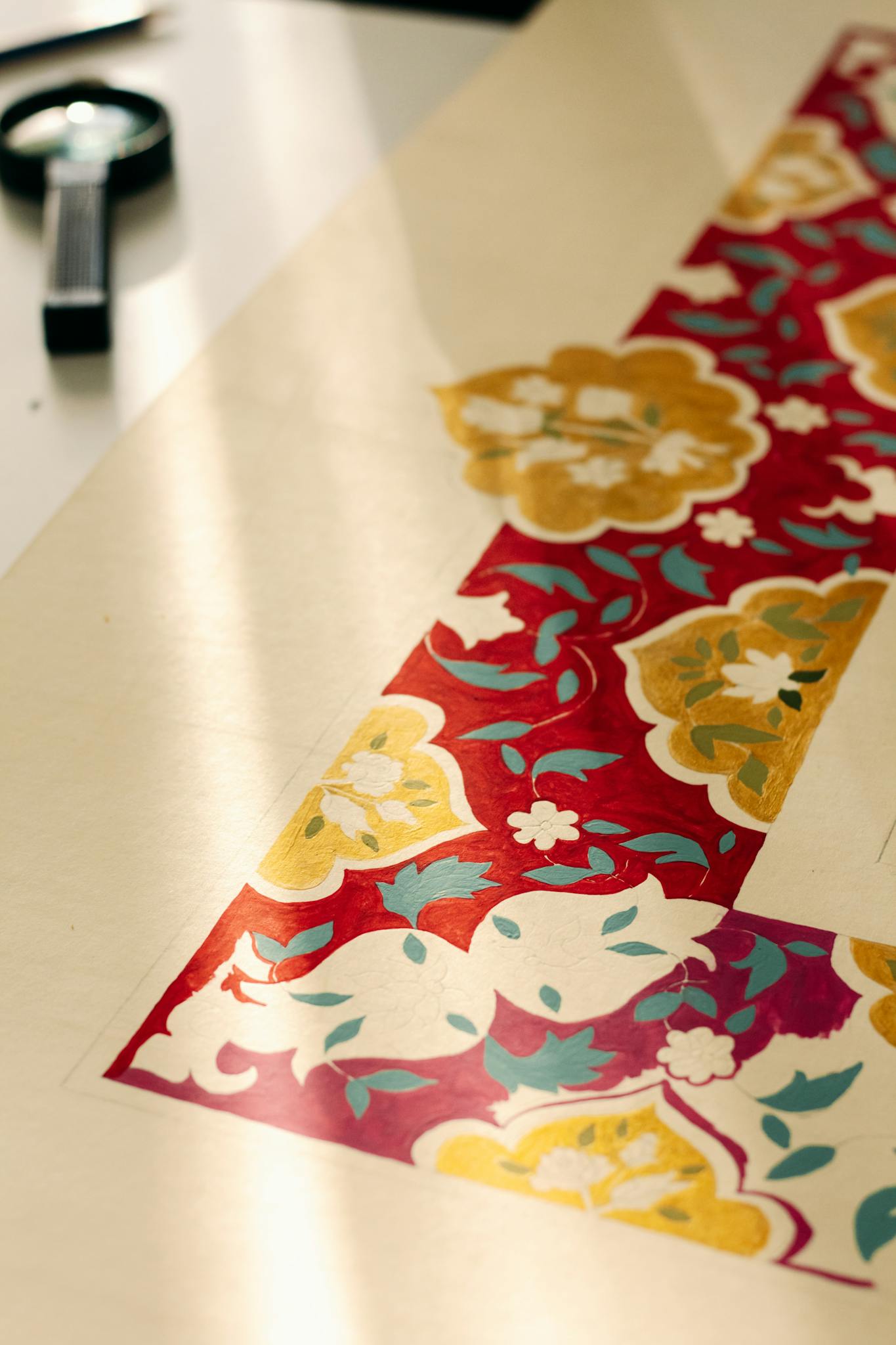 Close-up of traditional floral pattern on art paper with warm sunlight.